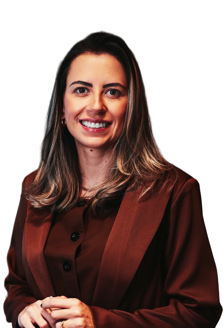 Dra. Raphaela Meyge de terninho marrom, sorrindo, com as mãos unidas